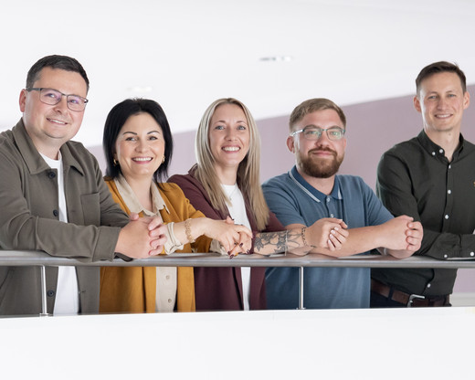 Gruppenfoto: Frauen und Männer lehnen am Geländer
